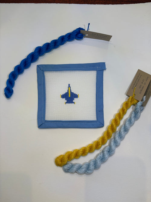 Small square fabric patch with a blue border and painted needlepoint design of a blue plane